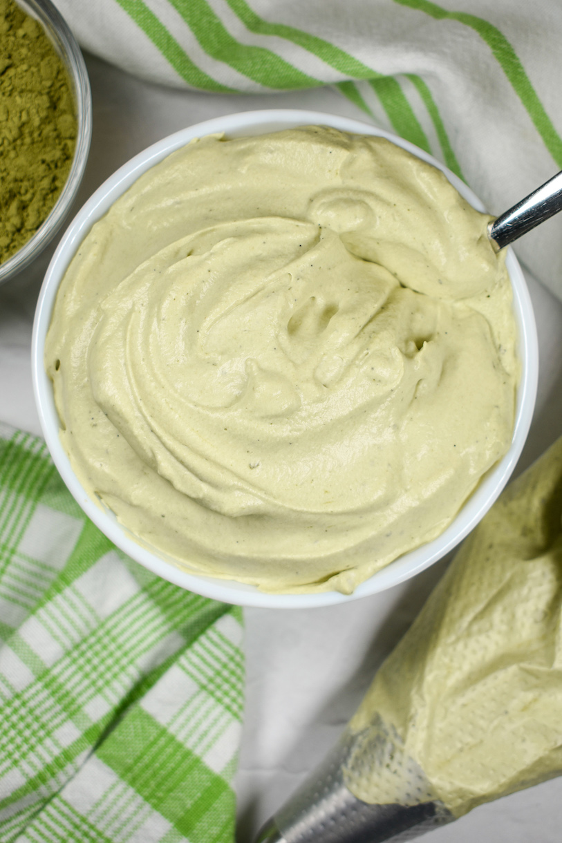 Looking down at a dish of matcha green tea whipped cream surrounded by green plaid and striped towels