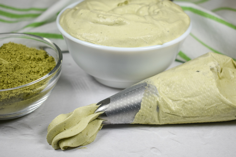 A piping bag of matcha whipped cream, dish of matcha, and a dish of whipped cream
