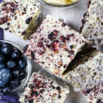 Vertical shot of blueberry krispie treats, dish of blueberries, and dish of white chocolate callets