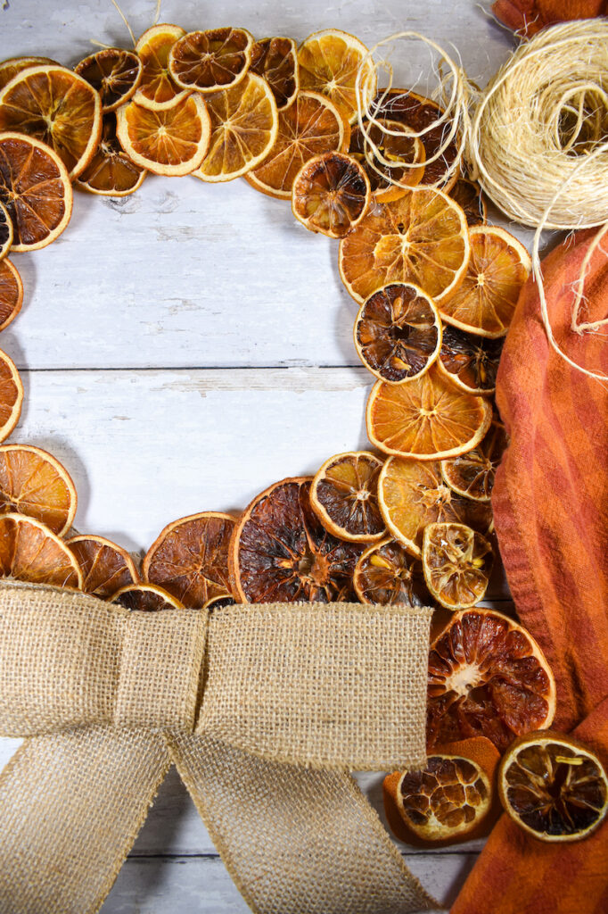 a citrus wreath decorated with a burlap bow