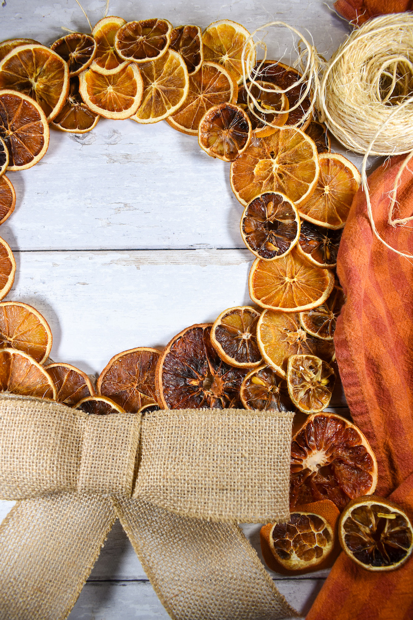 a citrus wreath decorated with a burlap bow