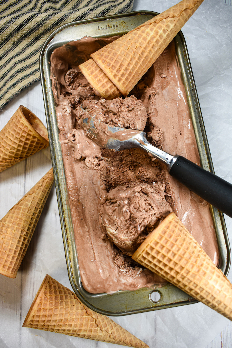 A loaf pan of no churn chocolate ice cream surrounded by sugar cones