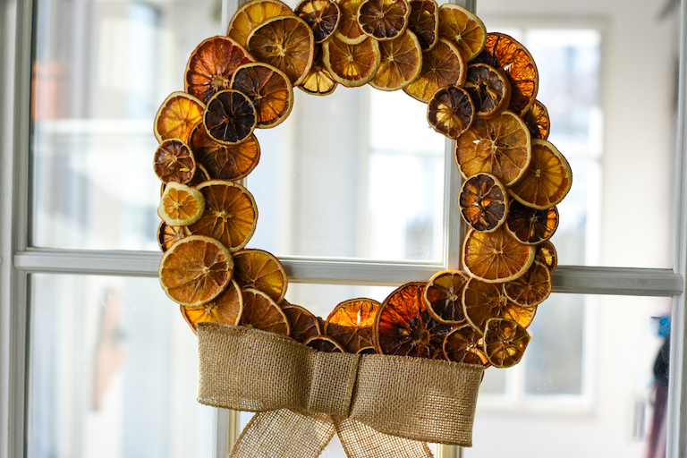 A citrus fruit wreath hanging in a window