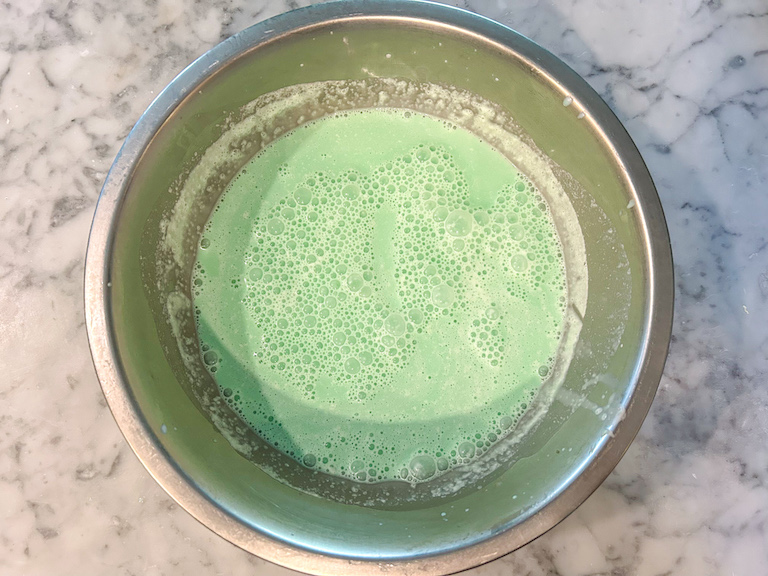 Mint green ice cream base in a metal bowl