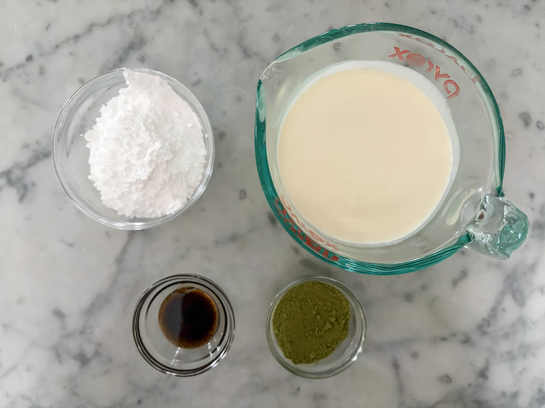 Matcha whipped cream ingredients arranged on a white surface
