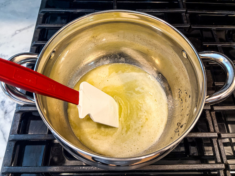 Melted butter in a stock pot on the stovetop with a spatula