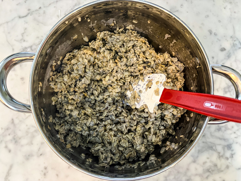 Blueberry cereal treat mixture in a stock pot with a rubber spatula