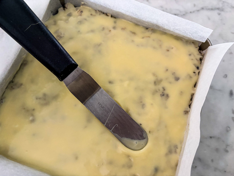 Palette knife spreading white chocolate over krispie treats