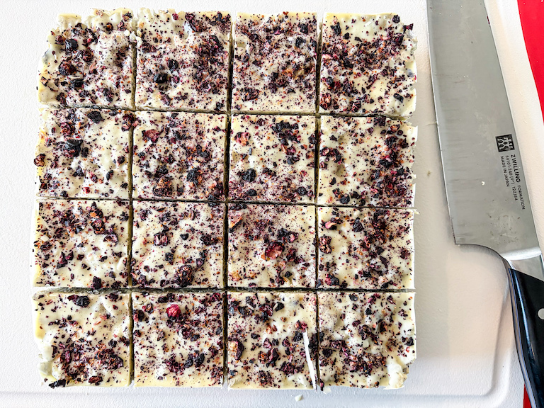 Sliced blueberry krispie treats on a cutting board with a knife