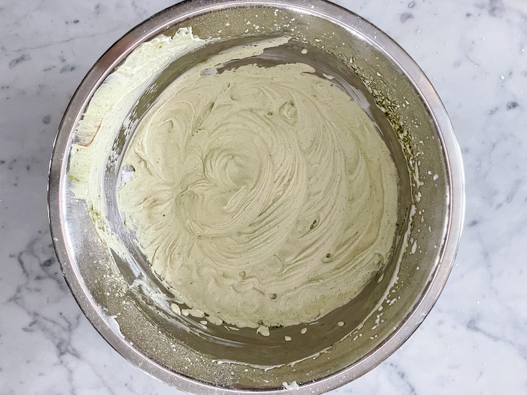 A bowl of matcha whipped cream on a marble surface