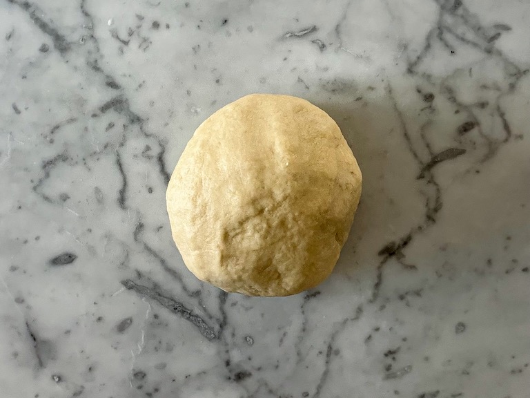 Loaf of bread dough on marble countertop