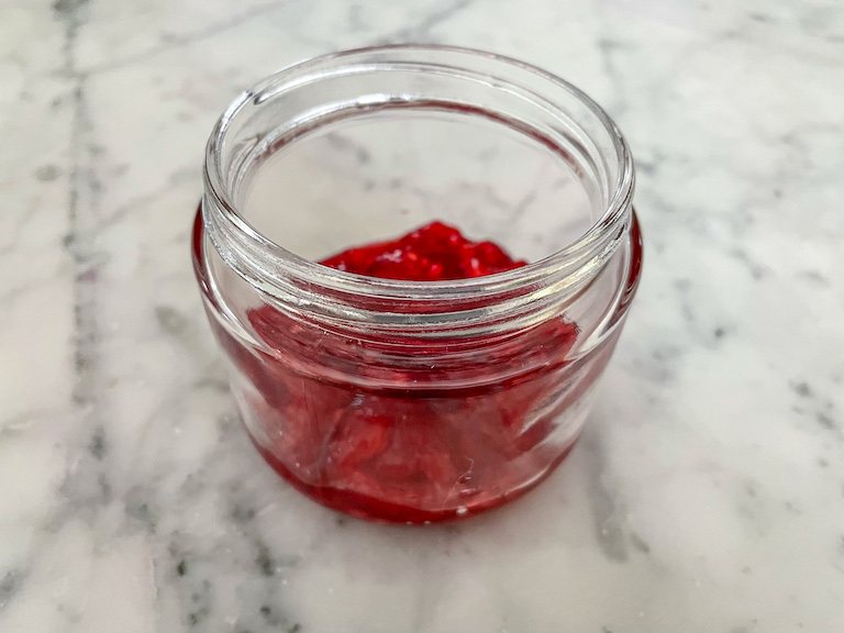 Macerated raspberries spooned into a jar