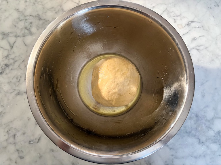 A ball of dough in a metal bowl