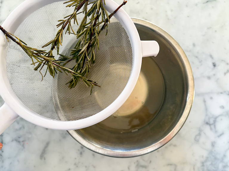 straining rosemary through a fine mesh strainer