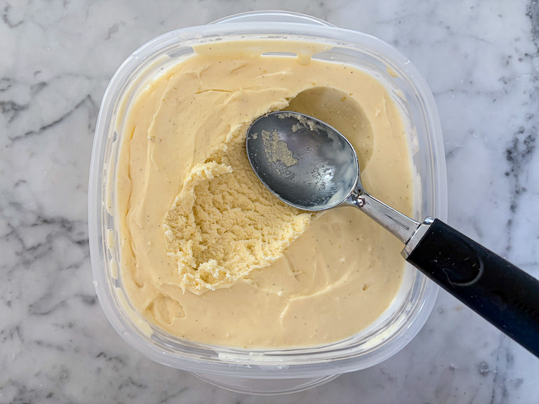 A container of cheesecake ice cream with an ice cream scoop