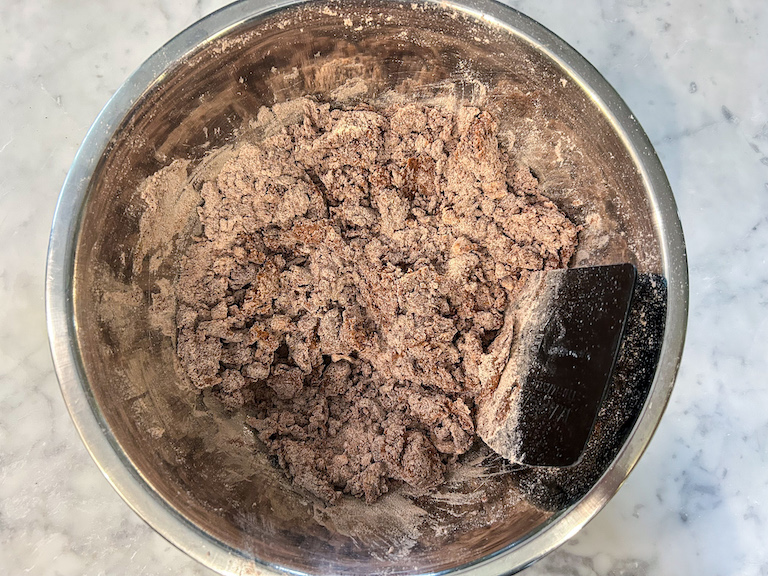 Mixing biscotti dough with a bench scraper