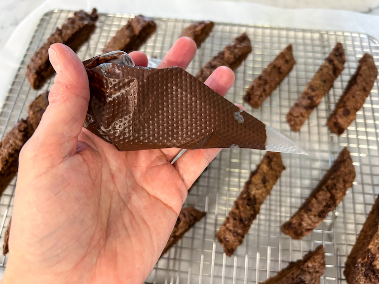 Hand holding a piping bag of melted chocolate