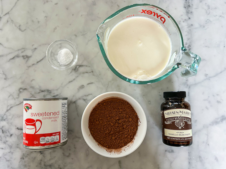 No churn chocolate ice cream recipe ingredients on a marble surface