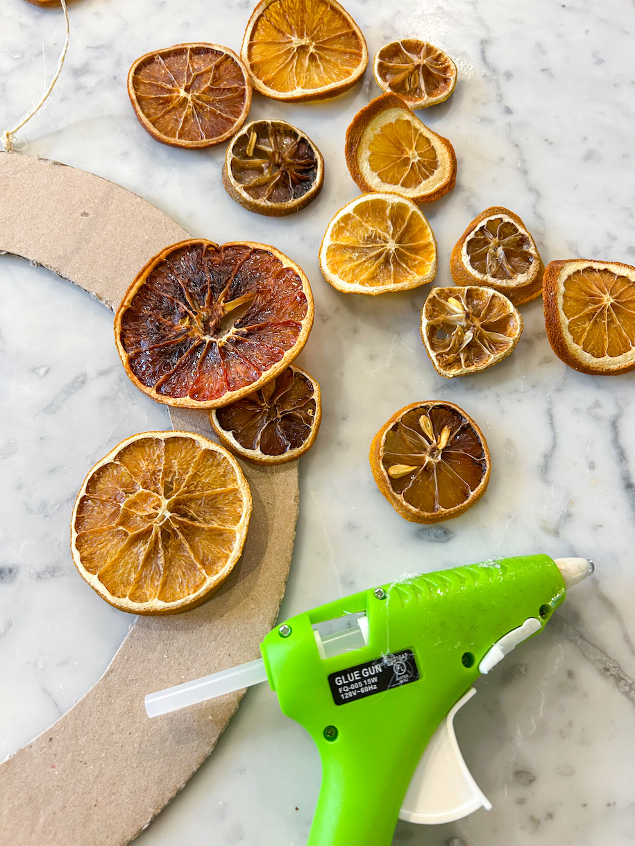 Assembling a citrus fruit wreath with a hot glue gun