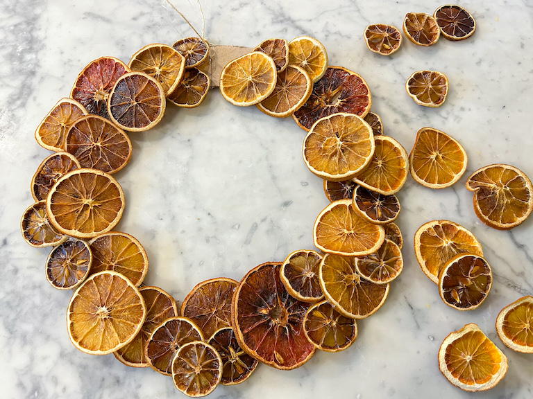 Assembling a dried citrus fruit wreath on a marble surface