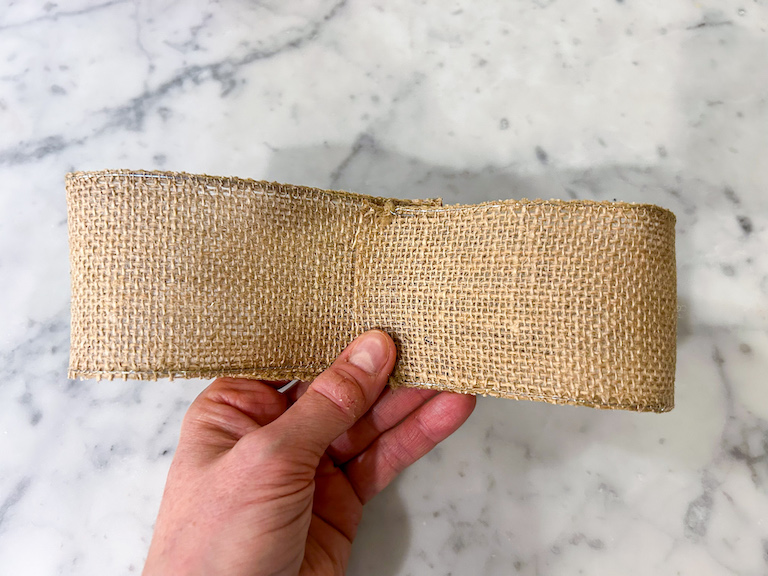 Hand holding part of a burlap ribbon bow