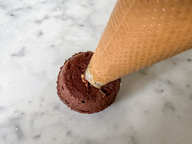 Piping bag filling a mini muffin with peanut butter