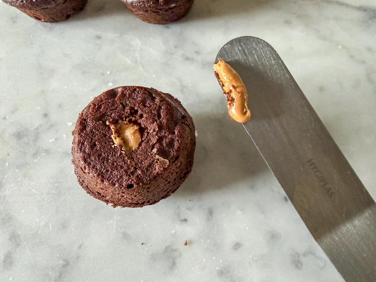 Palette knife scraping excess peanut butter from a mini muffin