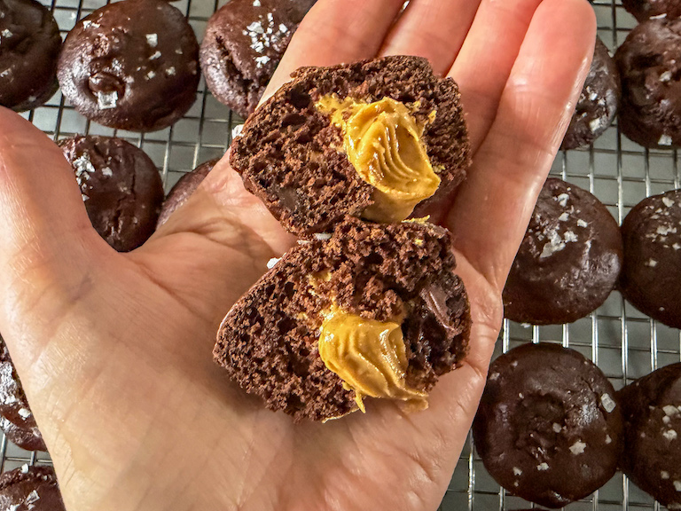 Hand holding a halved peanut butter chocolate mini muffin