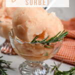 A dish of grapefruit sorbet garnished with sprigs of fresh rosemary