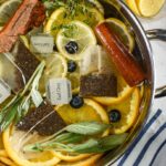 Earl Grey simmer pot arranged on a white surface with striped towels and dishes of citrus fruit
