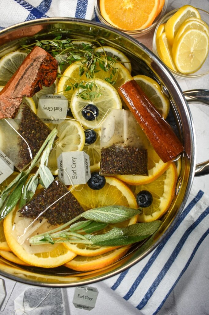 Earl Grey simmer pot arranged on a white surface with striped towels and dishes of citrus fruit