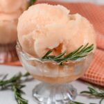 A dish of grapefruit sorbet garnished with sprigs of fresh rosemary
