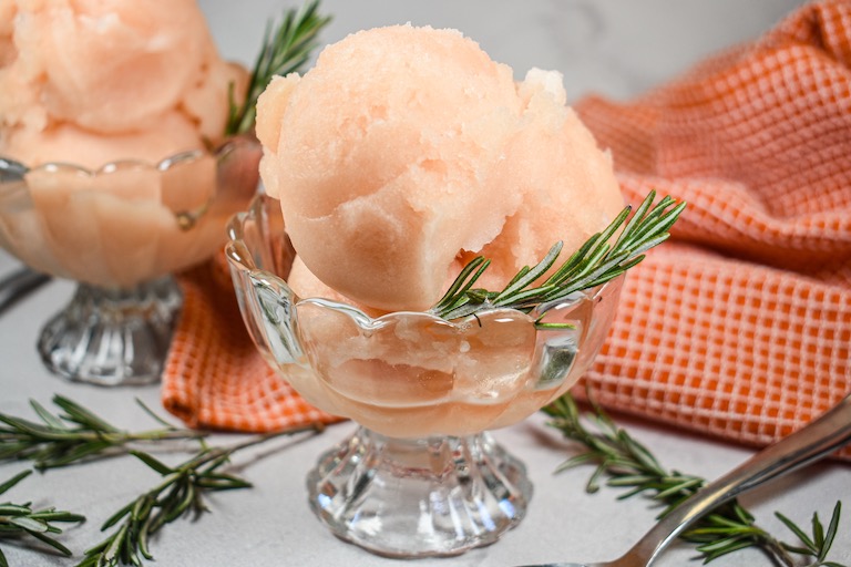A dish of grapefruit sorbet with sprigs of fresh rosemary