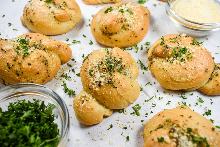 Garlic knots with parmesan and chopped herbs sprinkled over top