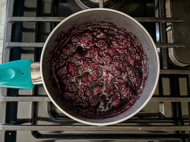 Blackberries and sugar simmering in a pan on the stovetop