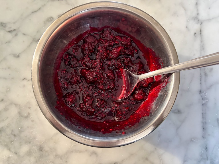 A dish of blackberry compote with a spoon