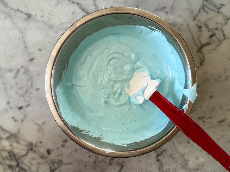 A bowl of blue marshmallow fluff with a spatula