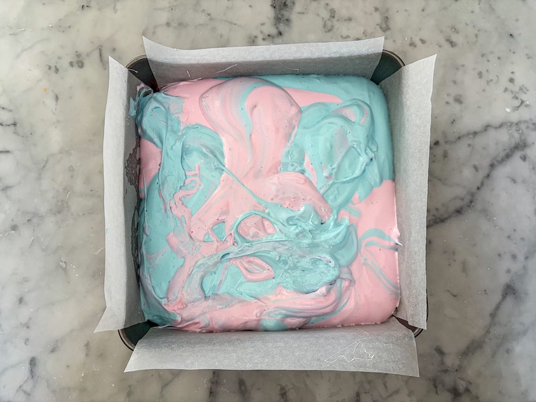 Swirls of pink and blue marshmallow in a parchment lined tin