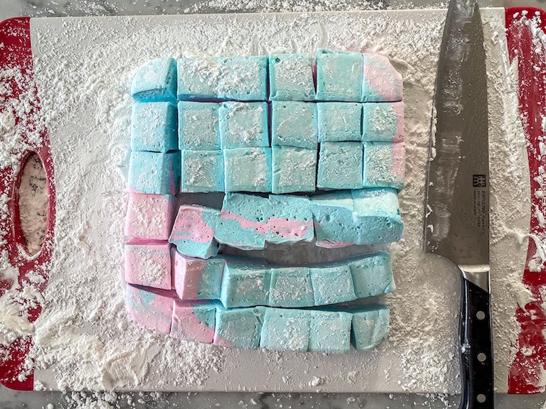 Slicing pink and blue marshmallows with a chef's knife