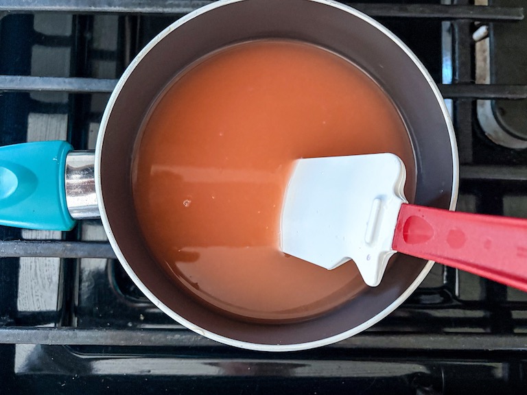 Grapefruit juice in a pan on the stovetop with a spatula