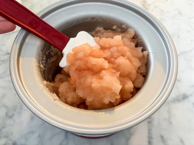 Scooping churned grapefruit sorbet with a rubber spatula