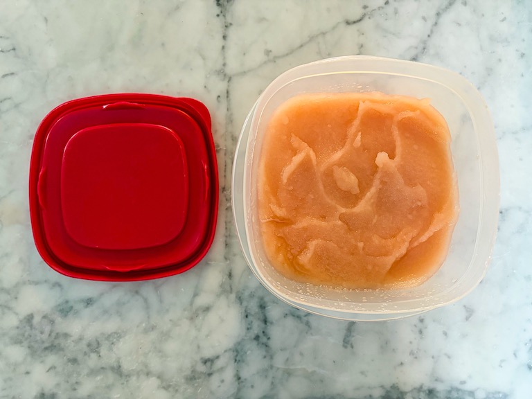 Grapefruit sorbet in a plastic container with a red lid