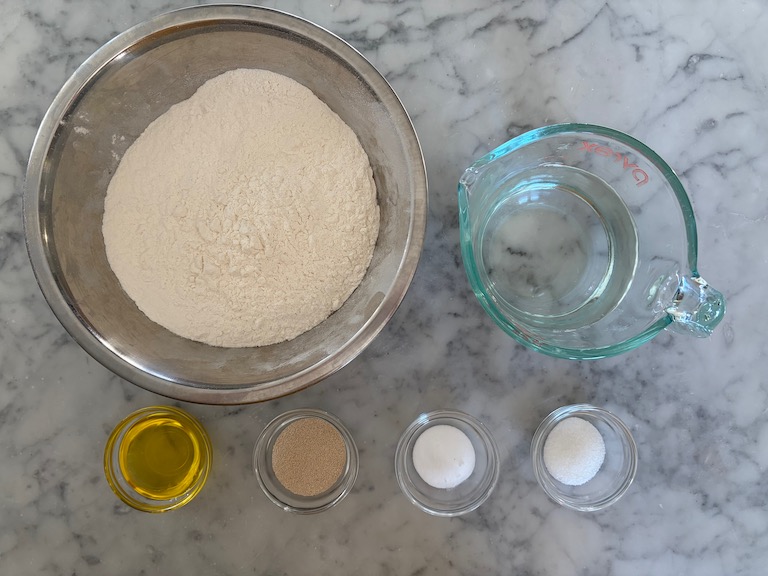 Garlic knot dough ingredients arranged on a marble surface