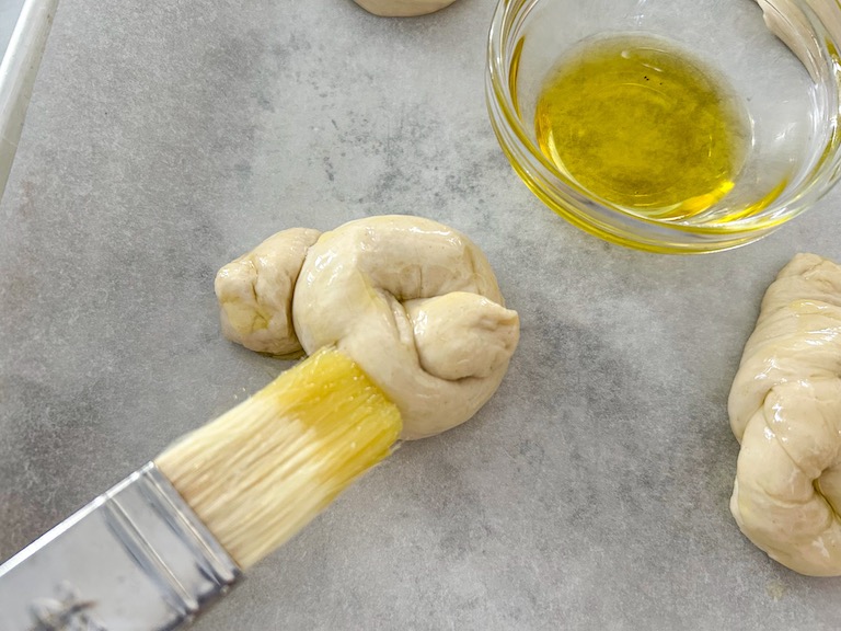 Brushing olive oil over an unbaked garlic knot