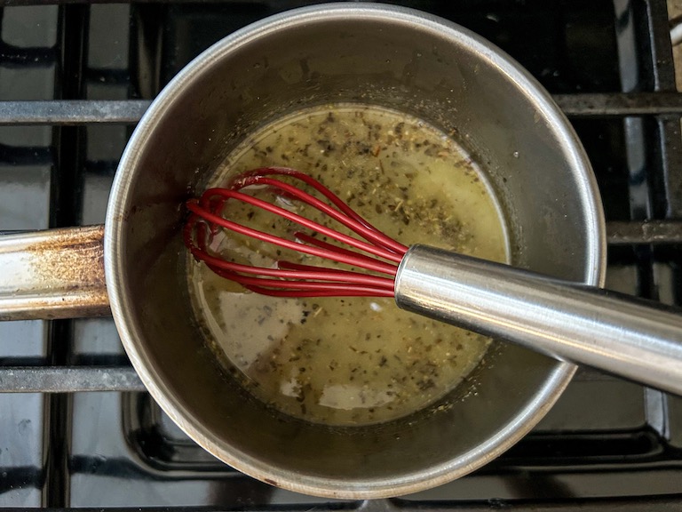 A pan of garlic butter with a whisk