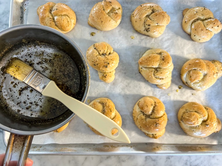Pan and brush brushing garlic butter on homemade garlic knots