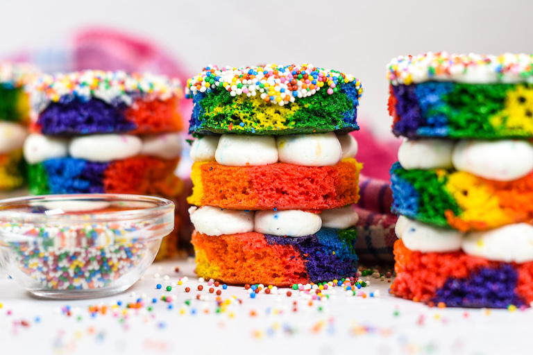 A row of rainbow dot cakes with a bowl of rainbow nonpareils