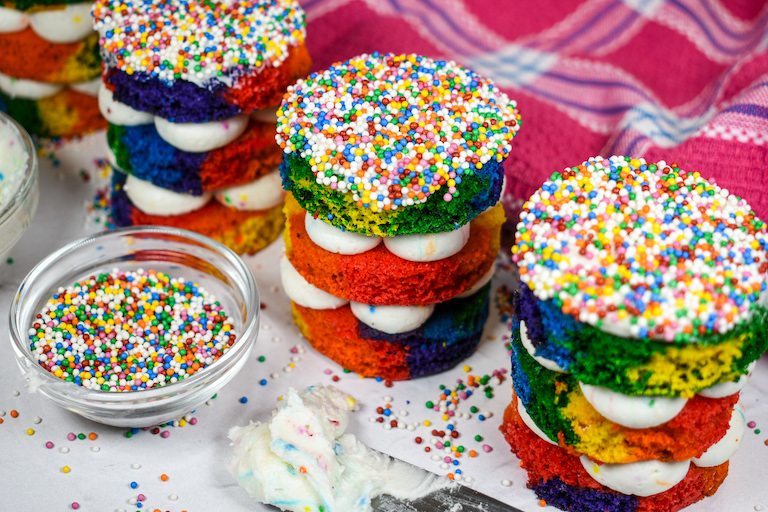 Rainbow dot cakes with a pink plaid towel and dish of sprinkles