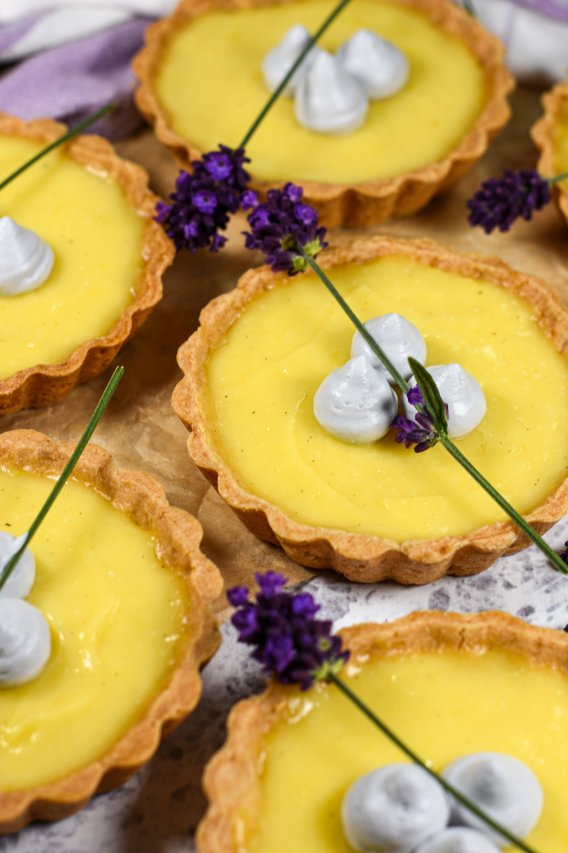 Lemon tarts with lavender arranged on a textured white surface