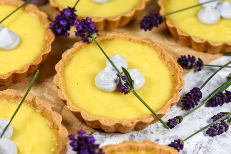 Miniature lemon tarts garnished with lavender whipped cream and lavender flowers